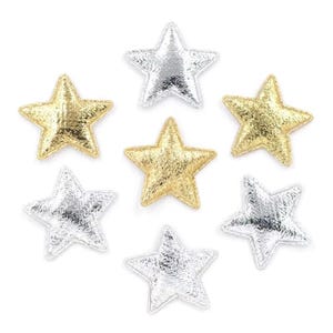 Op de afbeelding: Zeven stervormige stoffen patches in goud en zilver. De patches hebben een getextureerd uiterlijk en zijn gerangschikt op een witte achtergrond. De sterren zijn een decoratief element, mogelijk voor knutselen of versieringen.