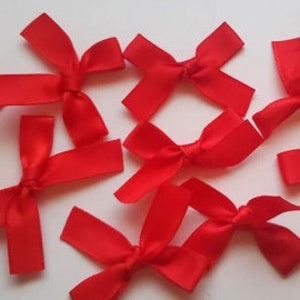 May include: A collection of ten red satin bows. The bows are tied in a simple knot and have a classic, elegant look.