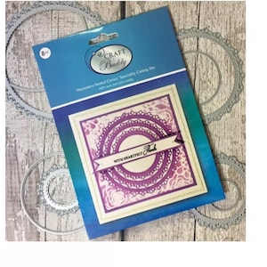 Puede incluir: Un paquete de 8 troqueles de corte especiales de círculos anidados decorativos. Los troqueles son plateados y tienen un diseño delicado. El paquete muestra una tarjeta de muestra con los troqueles utilizados para crear un diseño de círculo en capas con las palabras "With Heartfelt Thanks".