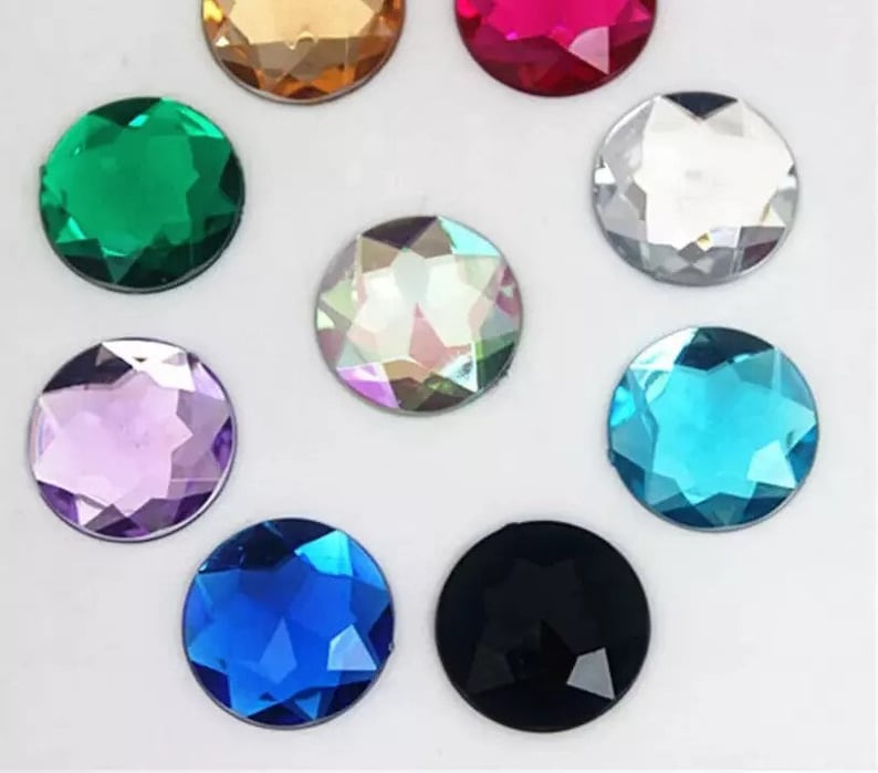 May include: Assortment of ten round, faceted, glass rhinestones in various colours, including clear, black, green, blue, purple, turquoise, and iridescent.