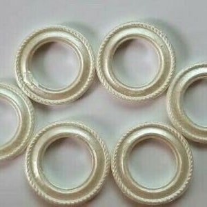 May include: Six white metal curtain rings with a decorative edge. The rings are arranged in a circle.