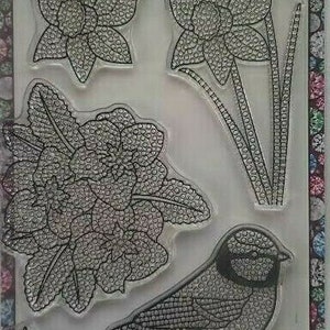 以下が含まれることがあります： 花と鳥のデザインが特徴のクリアスタンプセット。スタンプには、花と鳥の詳細な画像が含まれており、すべてドットパターンです。セットには「Crystal Art Stamps Hello Spring」と表示されています。