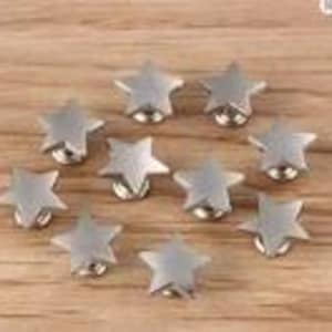 May include: A collection of nine small, five-pointed star-shaped metal knobs with a brushed silver finish. Each star features a central circular base attachment, providing a uniform appearance across the set of decorative hardware pieces.