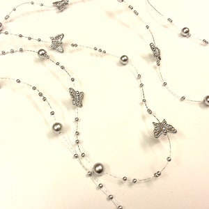 May include: Silver butterfly garland with pearl beads. The garland is made of clear wire and is perfect for adding a touch of sparkle to any occasion.