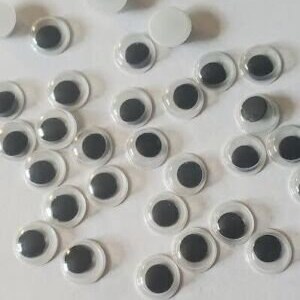 May include: A collection of googly eyes in various sizes, with black pupils and clear plastic surrounds. The googly eyes are arranged on a white surface.