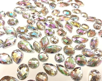 May include: Assortment of iridescent clear glass rhinestones in various shapes and sizes. The rhinestones have a rainbow effect.