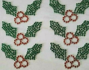 May include: A sheet of green and red rhinestone iron-on appliques in the shape of holly leaves and berries.
