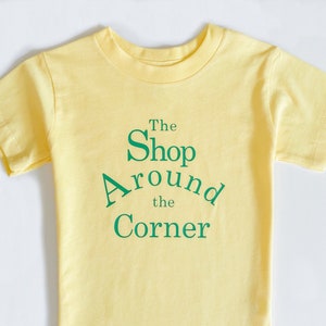 La maglietta per bambini SHOP AROUND The CORNER o la tutina per neonati - C&#39;è posta per te, regalo per la festa del film - C&#39;è posta per te, stampa con biglietto - Design per maglietta