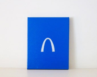 May include: A blue canvas painting with a white outline of the St. Louis Arch.
