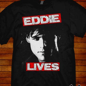 May include: Black t-shirt with a white image of a person's face and the text "EDDIE LIVES" in red.