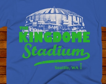 Könnte beinhalten: Ein königsblaues T-Shirt mit einer grünen Grafik des Kingdome Stadiums in Seattle, Washington. Der Text lautet "The Kingdome Stadium, Seattle, WA".