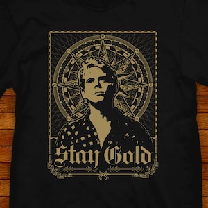 May include: Black t-shirt with a gold graphic of a man with a compass and the text "Stay Gold".
