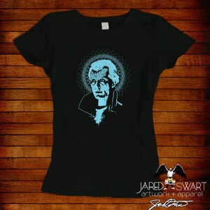 May include: Black t-shirt with a blue graphic of a man's face with a geometric pattern behind it. The text "JARED SWART artwork + apparel" is at the bottom of the shirt.