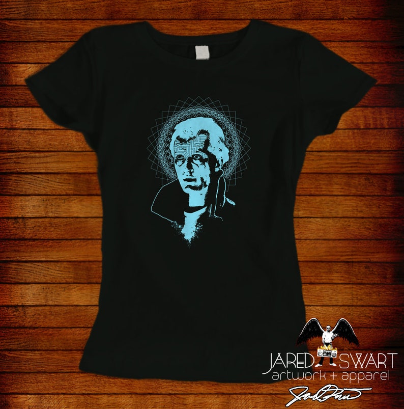 May include: Black t-shirt with a blue graphic of a man's face with a geometric pattern behind it. The text "JARED SWART artwork + apparel" is at the bottom of the shirt.