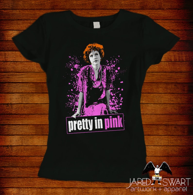 May include: A black t-shirt with a pink and white graphic of a woman in a pink dress with the text "pretty in pink" in pink letters.