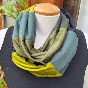 May include: A multi-colored infinity scarf with stripes of green, dark green, and blue.