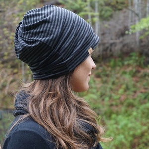 May include: A black and gray striped beanie hat. The hat is made of a soft, stretchy fabric and has a slouchy fit.