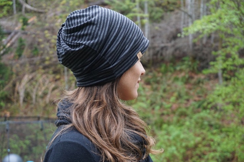 May include: A black and gray striped beanie hat. The hat is made of a soft, stretchy fabric and has a slouchy fit.