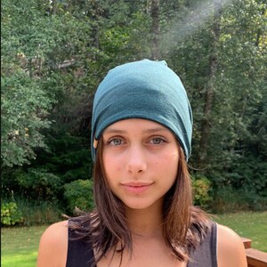 May include: A person wearing a teal blue beanie hat. The hat is made of a soft, stretchy fabric.