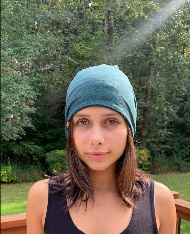 May include: A person wearing a teal blue beanie hat. The hat is made of a soft, stretchy fabric.