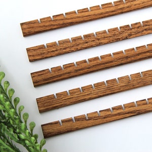 May include: Five wooden dowels with notches cut into the edges. The dowels are stained a dark brown colour.