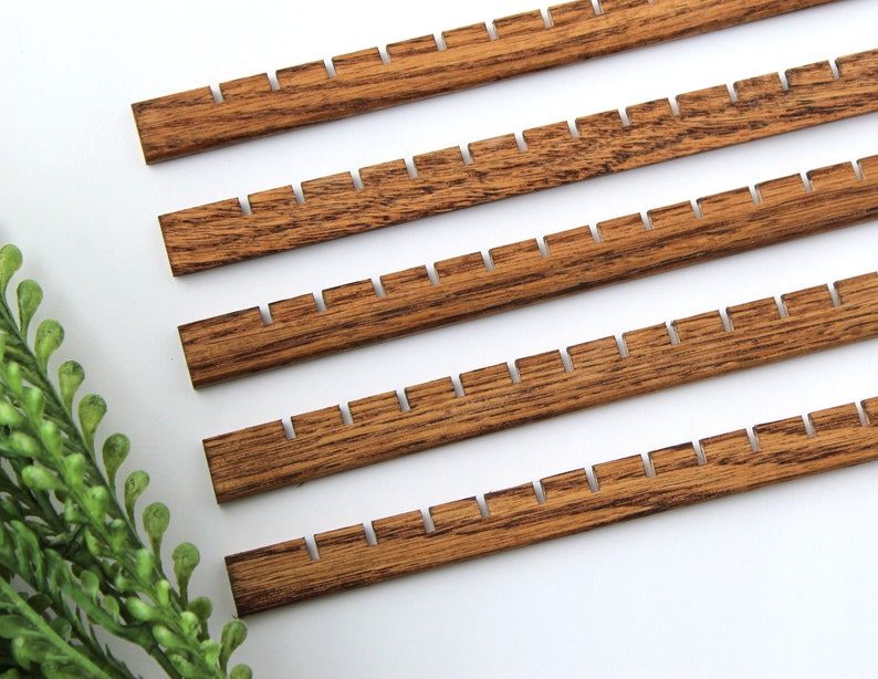 May include: Five wooden dowels with notches cut into the edges. The dowels are stained a dark brown colour.