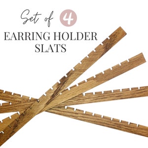May include: Set of 4 wooden earring holder slats. Each slat has a series of evenly spaced notches for hanging earrings.