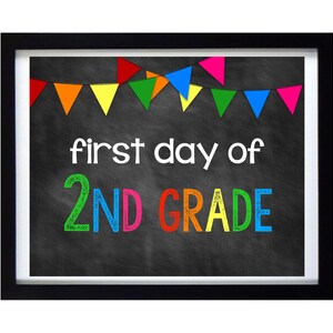 Könnte beinhalten: Ein Schild aus schwarzer Tafel mit einem schwarzen Rahmen und bunten Wimpelflaggen oben. Das Schild sagt "first day of 2ND GRADE" in bunter Kreide.