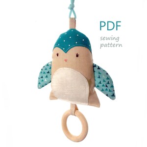 May include: PDF sewing pattern for a blue and white fabric owl toy with a wooden ring.