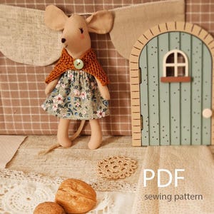 May include: A handmade fabric mouse doll wearing a floral dress and a knitted orange shawl. A small wooden door and two walnuts are in the foreground. The text "PDF sewing pattern" is visible.