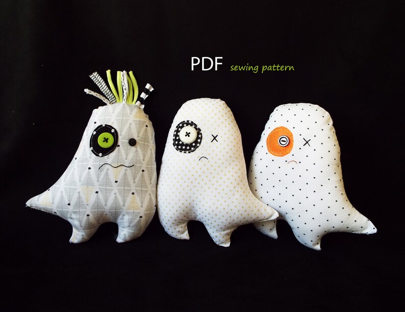 May include: Three handmade fabric monster dolls with button eyes and stitched faces. The dolls have different patterned fabrics and colors, including white, gray, and black. The text "PDF sewing pattern" is visible.