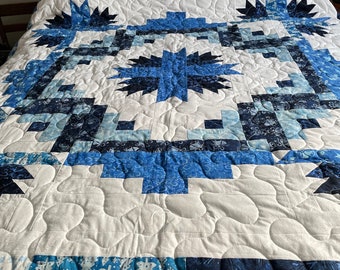 Christmas or winter themed queen size quilt in shades of blue on a white background.