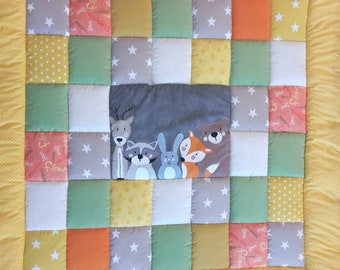 Peut inclure: Une courtepointe en patchwork avec une variété de couleurs et de motifs, notamment le jaune, le vert, l'orange et le gris. Le centre de la courtepointe présente un panneau avec un cerf, un raton laveur, un lapin et un renard. La courtepointe est entourée d'une bordure jaune.