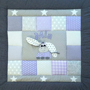 Puede incluir: Una alfombra de juego para bebés de patchwork gris y morado con una linda aplicación de animal morado y blanco y el nombre "Mia" bordado.