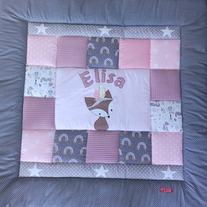 Może przedstawiać: Różowo-szara patchworkowa kołderka dla niemowląt z wzorem lisa i wyhaftowanym imieniem "Elisa". Kołderka wykonana jest z różnych materiałów, w tym waflowego, z gwiazdkami i tęczami.