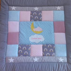 Könnte beinhalten: Eine graue und weiße Patchwork-Babydecke mit einem blauen und weißen Mond- und Wolken-Design. Die Decke hat ein rosa und weißes Karomuster, ein blaues und weißes Sternenmuster und ein graues und weißes Regenbogenmuster. Die Decke ist mit dem Namen "Lovina June" personalisiert.
