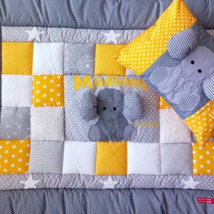 Könnte beinhalten: Eine graue und gelbe Patchwork-Babydecke mit einem gestickten Elefanten und dem Namen "Madeleen" sowie dem Datum "26.01.2023". Ein passendes Kissen mit einem gestickten Elefanten und dem Namen "Madeleen" ist ebenfalls enthalten.