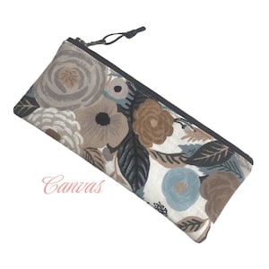 May include: A zippered pencil case with a floral print featuring brown, blue, and white flowers on a white background. The zipper pull is black.
