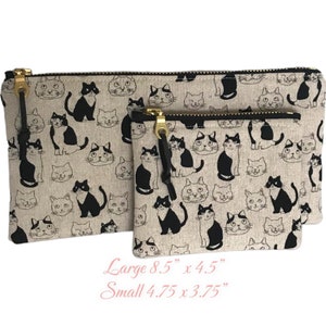 May include: Two zippered pouches with a black and white cat print on a beige background. The larger pouch measures 8.5 inches by 4.5 inches and the smaller pouch measures 4.75 inches by 3.75 inches.