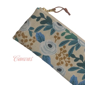 May include: A beige canvas zippered pouch with a floral pattern featuring white, blue, and brown flowers. The zipper pull is brown leather.