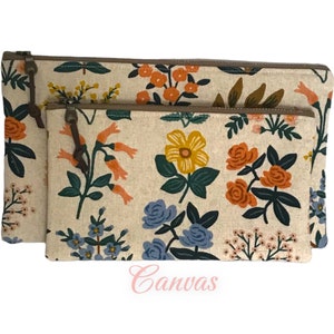 May include: Two canvas zipper pouches with a floral pattern. The pouches feature a cream-colored background with orange, yellow, blue, and green flowers. The zippers are brown, and the pouches have a leather pull tab.