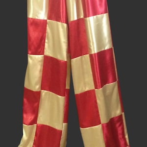 May include: Checkered pants with red and gold squares. The pants are made of satin and have a high waist.