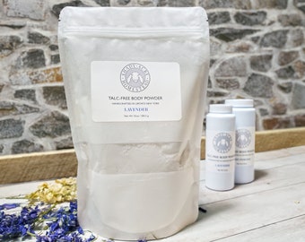 Könnte beinhalten: Ein weißer wiederverschließbarer Beutel gefüllt mit weißem Pulver, beschriftet mit "Talkfreier Körperpuder" mit dem Duft "Lavendel". Der Beutel wird in Upstate New York handgefertigt. Zwei kleinere weiße Flaschen mit dem gleichen Pulver sind im Hintergrund zu sehen.