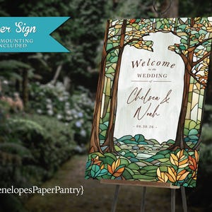 May include: A rectangular paper sign featuring a stained glass style forest illustration with green, brown, and orange tones. The centre text reads Welcome to the WEDDING of Chelsea & Noah 04.30.26. The sign is displayed on a metal easel stand.
