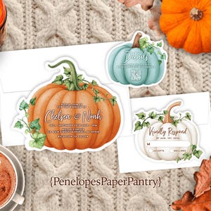 May include: A collection of fall-themed wedding stationery featuring pumpkin designs. The invitation card is orange with the names "Chelsea & Noah" and event details. Other cards include a teal and white pumpkin with text. A cup of coffee and a candle are also present.