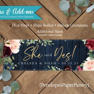 May include: A navy blue vinyl banner with a rustic woodgrain background and floral accents. The banner says "She said Yes!" with the names "Chelsea & Noah" and the date "09.15.23". The banner is 24 inches by 72 inches.
