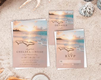 May include: A wedding invitation suite featuring a beach sunset scene with two hearts drawn in the sand. The cards include text for Chelsea and Noah, details, and an RSVP. A small white ring dish holds two silver rings, and a blue glass bottle is visible.