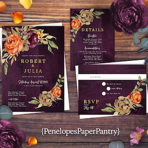 May include: Wedding invitation suite with a dark wood grain background. The invitation features the names "Robert & Julia" in gold lettering, along with floral accents in orange, burgundy, and green. Includes RSVP and details cards.