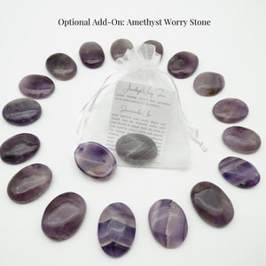 May include: A set of 12 amethyst worry stones in a white organza bag. The stones are smooth and oval shaped, with a purple and white color pattern. The bag includes a small card with information about amethyst worry stones.