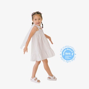Può includere: Una bambina che indossa un vestito bianco senza maniche con un orlo a balze e un fiocco bianco. Indossa sandali bianchi e ha i capelli in due trecce con fermagli colorati. L'immagine include un cerchio blu con il testo "Pdf sewing pattern Summer Dress & Top Girls  M/us letter 40 pile projector sizes: 2yrs-10yrs".